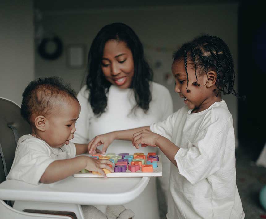 Woman watching her elder child play with her younger sibling